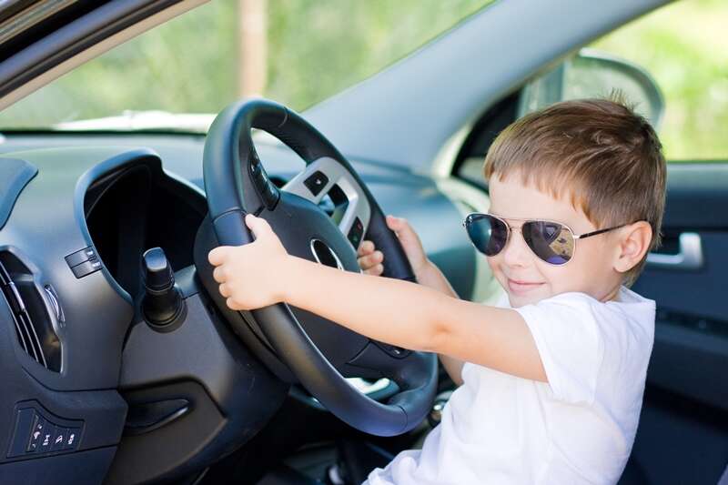 child in sunglasses driving a car