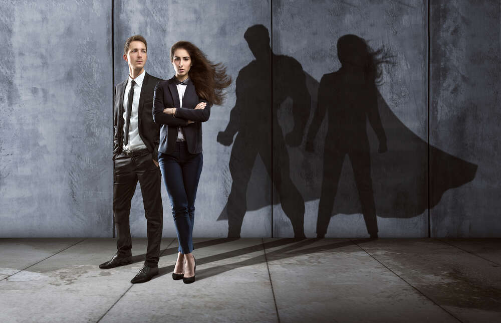 Man and Woman in business clothing casting super hero shadows