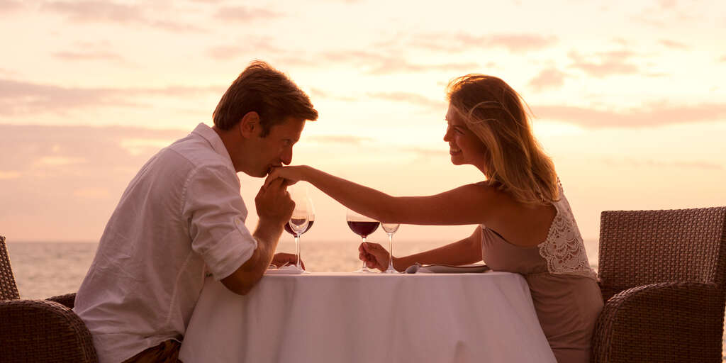 couple dining by water at sunset