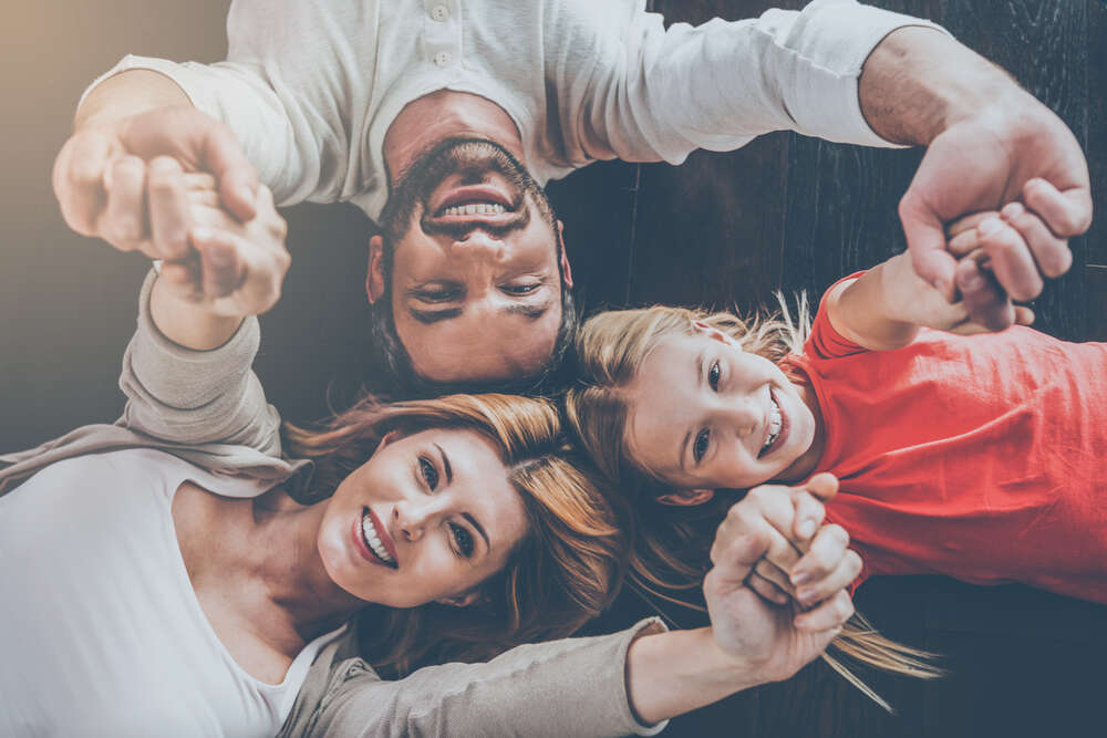 Mother, Father and Daughter laying on the floor, holding hands